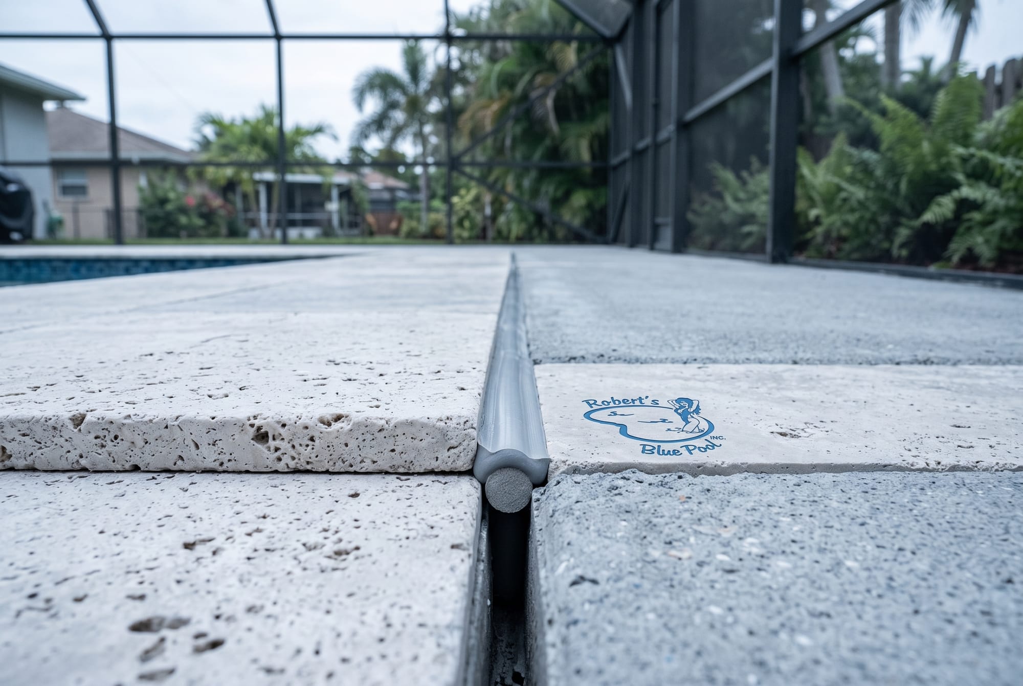 Fresh flexible sealant in the expansion joint between travertine coping and a concrete Miami pool deck