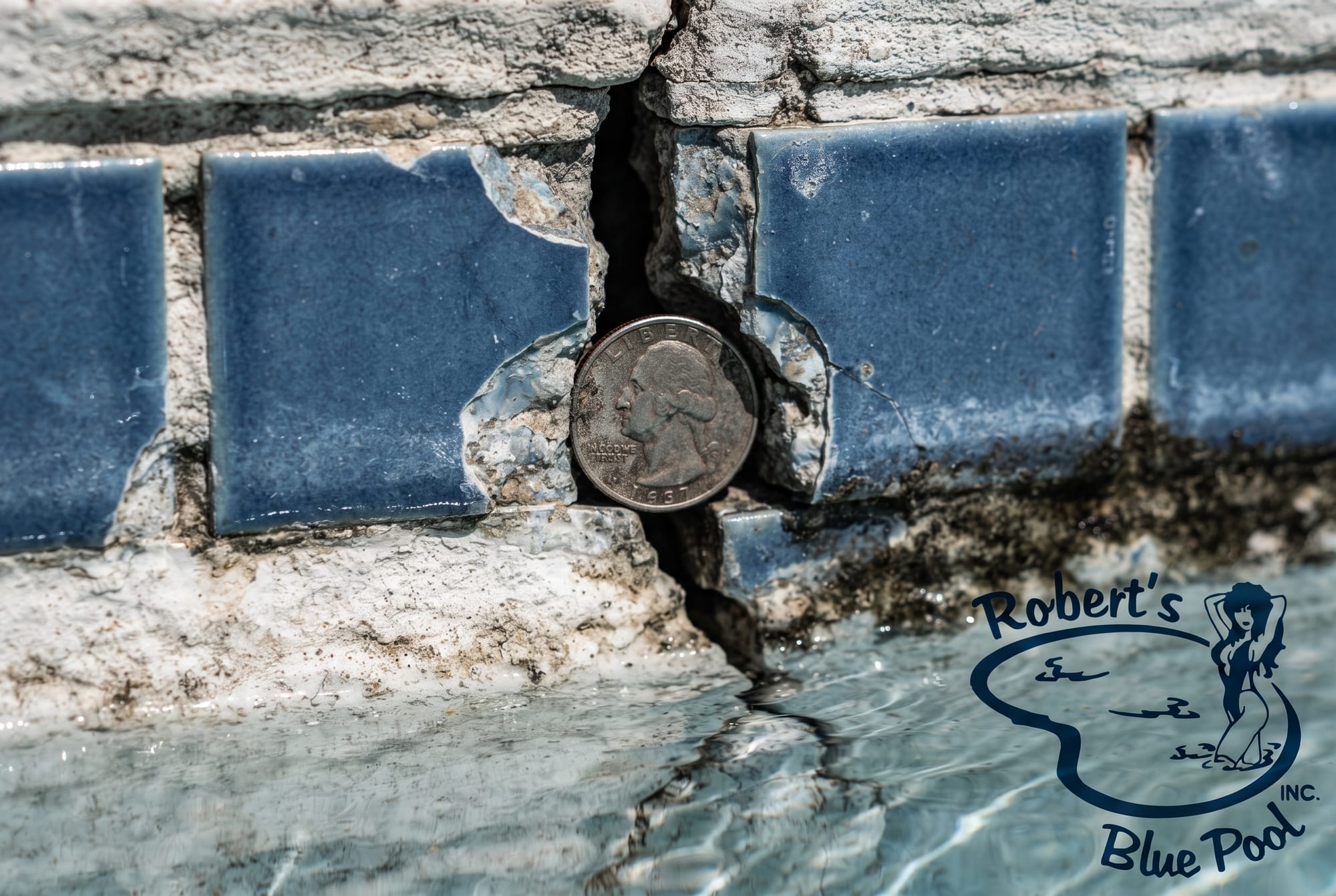 Close-up of cracked pool waterline tile on an aging Miami pool with a quarter showing the crack width
