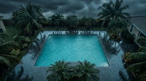 Miami residential pool overflowing during heavy rainstorm with dark clouds and palm trees