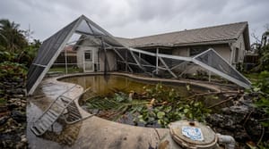 Miami backyard pool with storm debris and a bent screen enclosure the morning after a tropical storm