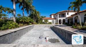 Drained Miami backyard pool mid-resurfacing on a clear dry-season day with royal palms and blue sky